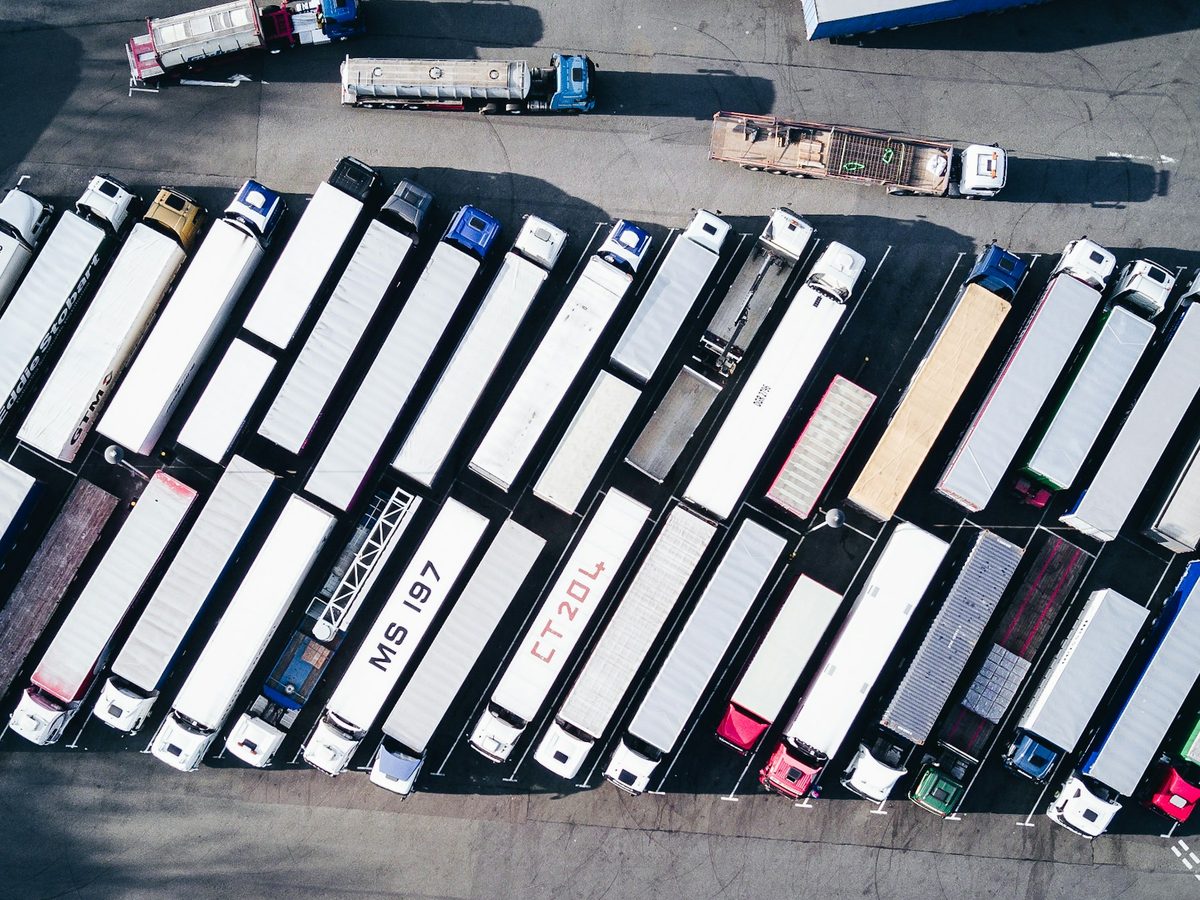 Vista aerea de un patio de maniobras con tractomulas de carga estacionadas en filas.